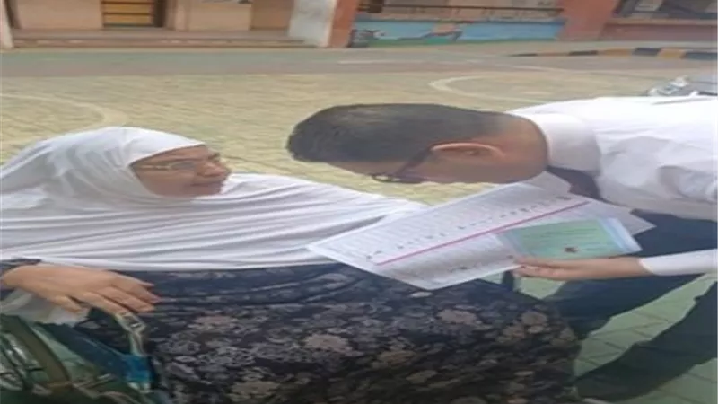 رئيس لجنة انتخابية يساعد مسنة على الإدلاء بصوتها في البحيرة